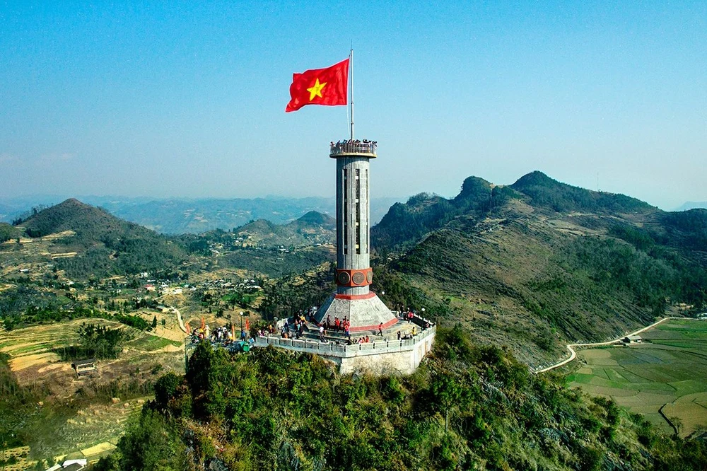 Le mât du drapeau national de Lung Cu s'élevant au sommet d'une montagne verdoyante.