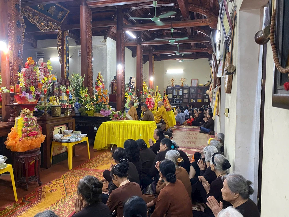 Des fidèles et villageois prient ensemble à l'intérieur de la pagode du village de Tri Lễ.