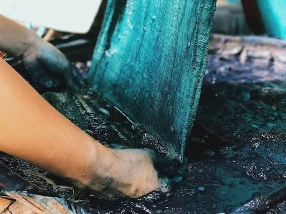 Teinture artisanale du tissu dans une cuve d'indigo.
